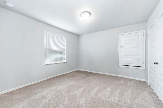 carpeted empty room featuring baseboards