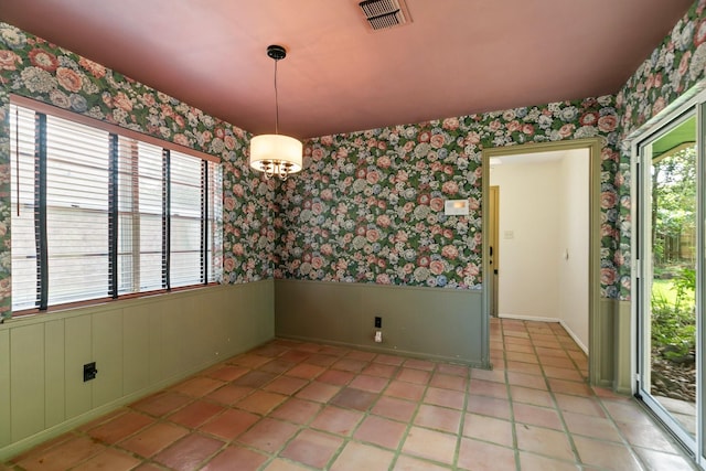 unfurnished dining area with wallpapered walls, visible vents, and wainscoting
