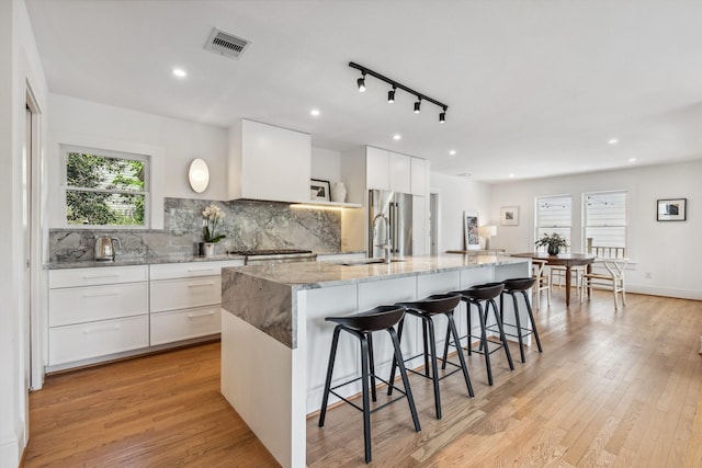 1202 Ashland St, Houston, TX 77008 - kitchen featuring a sink, a kitchen bar, a spacious island, tasteful backsplash, and light wood-style floors