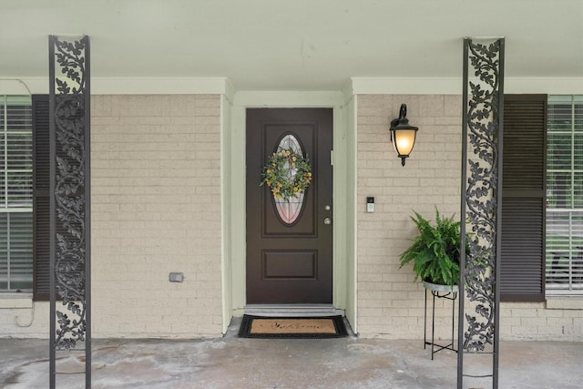 view of exterior entry with a porch and brick siding