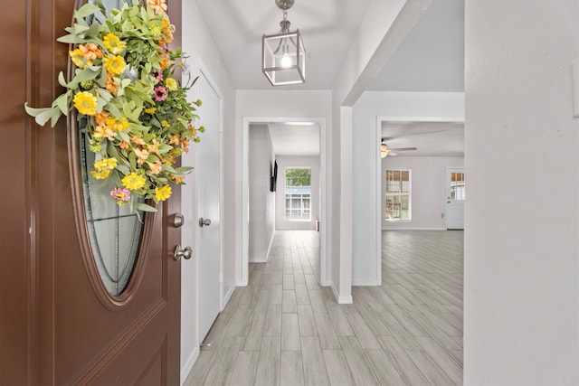 foyer with ceiling fan, light wood-style flooring, and baseboards