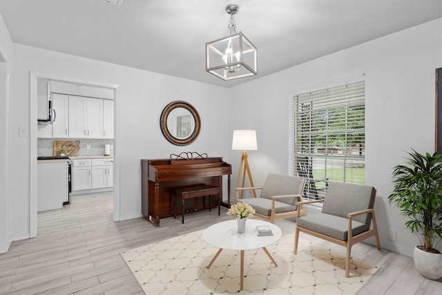 living area featuring baseboards, an inviting chandelier, and light wood finished floors