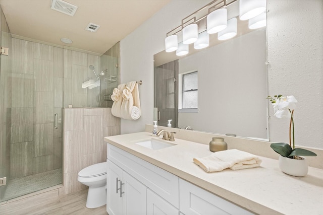 full bathroom with toilet, a stall shower, visible vents, and vanity