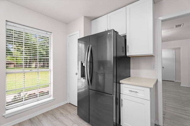 kitchen featuring light countertops, visible vents, black fridge with ice dispenser, and baseboards