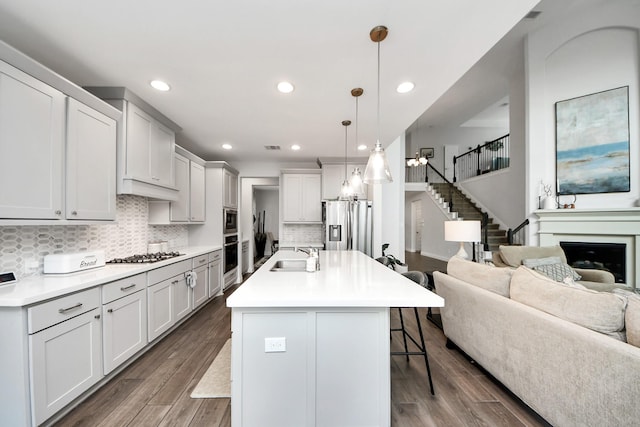 2242 Bayleaf Manor Dr, Manvel, TX 77578 - kitchen featuring wood finished floors, open floor plan, a kitchen bar, a sink, and appliances with stainless steel finishes