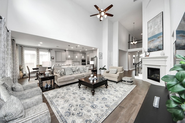 2242 Bayleaf Manor Dr, Manvel, TX 77578 - living area with a glass covered fireplace, ceiling fan with notable chandelier, wood finished floors, and a towering ceiling