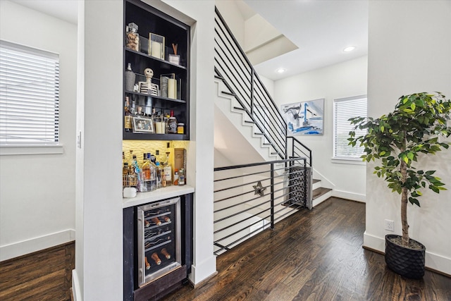 bar featuring wine cooler, wood finished floors, a bar, and a wealth of natural light
