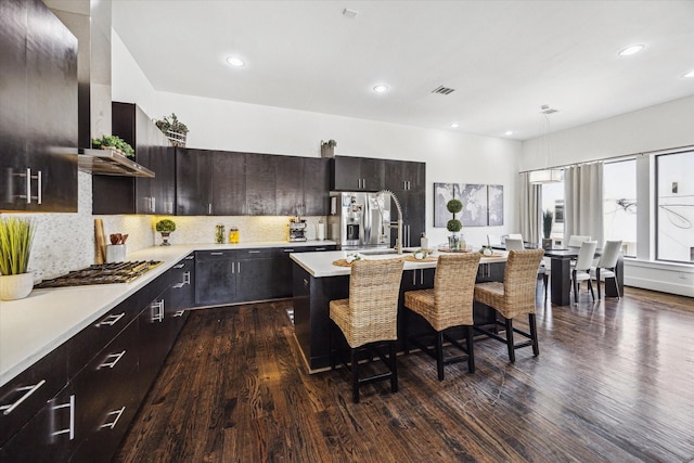 kitchen with a sink, decorative backsplash, a breakfast bar area, light countertops, and appliances with stainless steel finishes