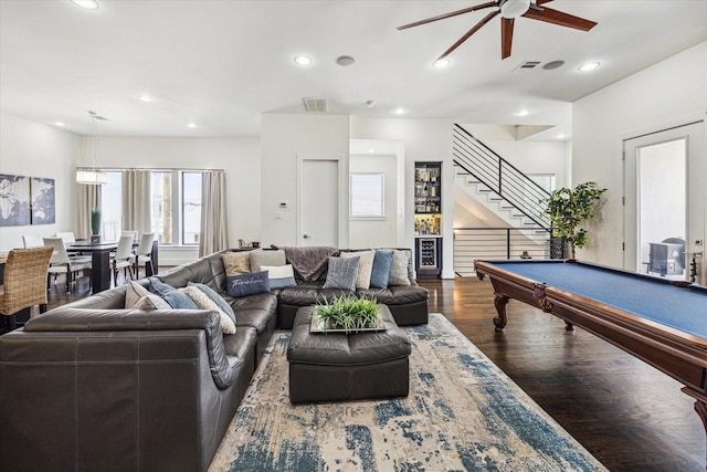 living area with a ceiling fan, visible vents, stairway, and wood finished floors