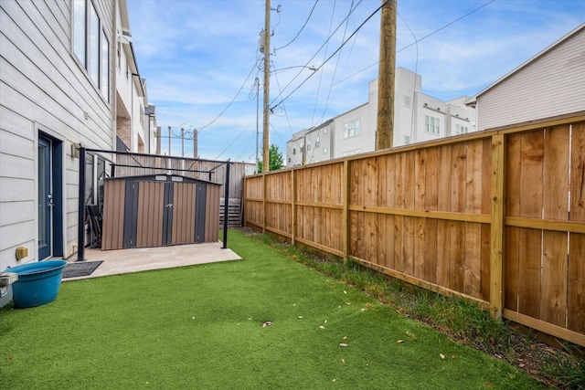view of yard with an outbuilding, a storage unit, and fence