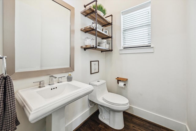 half bathroom featuring baseboards, wood finished floors, toilet, and a sink