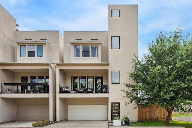 1505 Detering St, Houston, TX 77007 - townhome / multi-family property featuring a garage, driveway, stucco siding, and a balcony