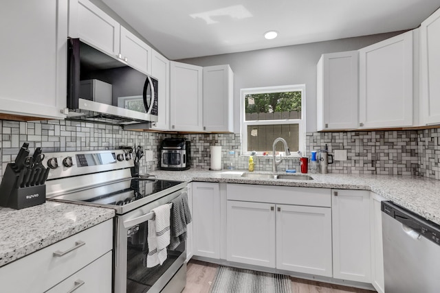 1315 Kilgore Rd, Baytown, TX 77520 - kitchen featuring a sink, decorative backsplash, white cabinets, and stainless steel appliances