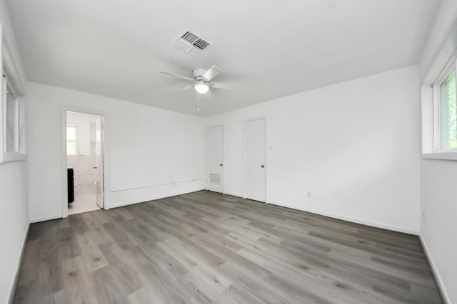 206 Hill St, Dayton, TX 77535 - unfurnished bedroom featuring ceiling fan, visible vents, ensuite bathroom, baseboards, and wood finished floors