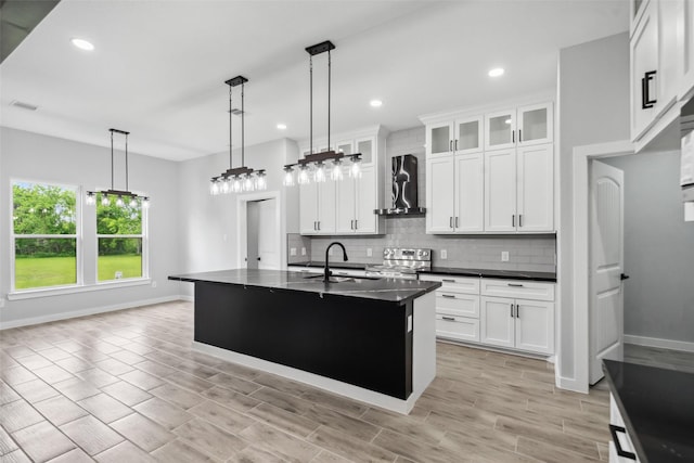 kitchen featuring tasteful backsplash, dark countertops, a sink, baseboards, and stainless steel range with electric stovetop