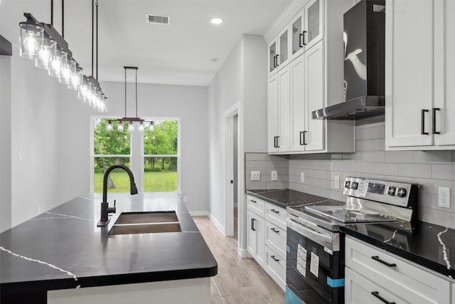 kitchen with stainless steel electric range oven, a sink, dark countertops, visible vents, and wall chimney exhaust hood