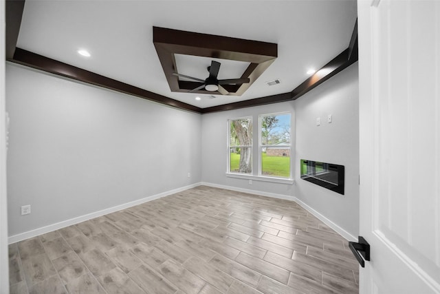 unfurnished living room featuring ceiling fan, a glass covered fireplace, visible vents, light wood-style flooring, and baseboards