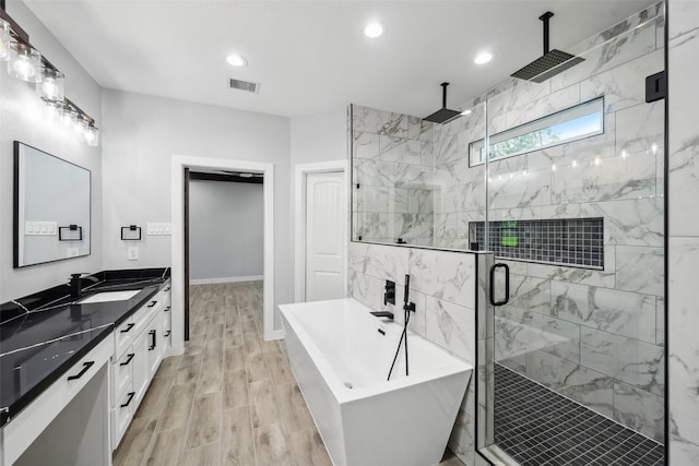 full bath with a soaking tub, visible vents, a stall shower, wood finished floors, and vanity