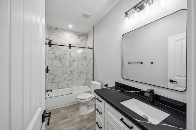 bathroom with visible vents, bath / shower combo with glass door, toilet, and vanity