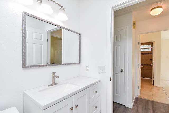 bathroom with baseboards, wood finished floors, and vanity