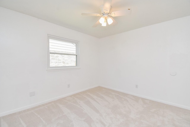 empty room with baseboards, a ceiling fan, and light colored carpet