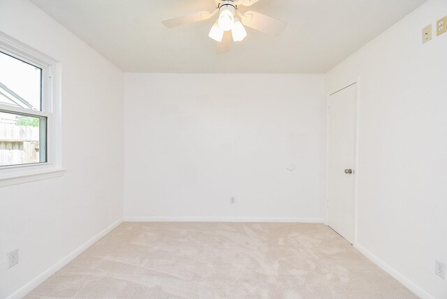 empty room with light colored carpet, ceiling fan, and baseboards