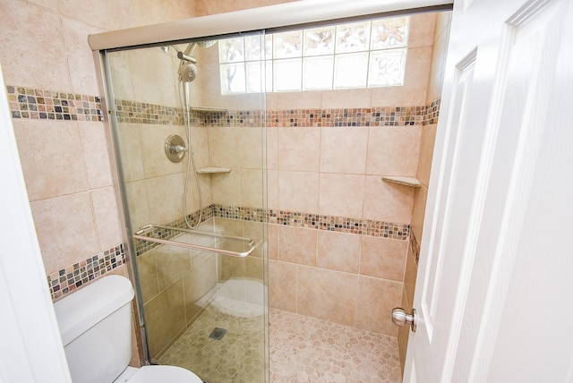 full bathroom with tile walls, a stall shower, and toilet