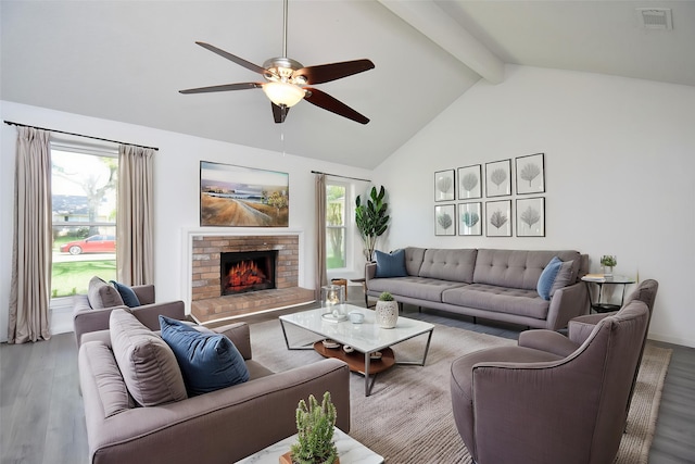 living room with wood finished floors, beamed ceiling, ceiling fan, a fireplace, and visible vents