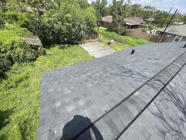 exterior details featuring fence and roof with shingles