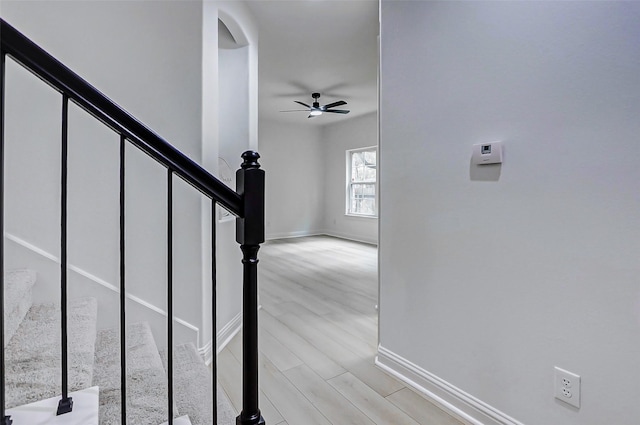stairs featuring baseboards, arched walkways, ceiling fan, and wood finished floors