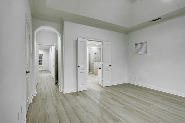 unfurnished bedroom with arched walkways, visible vents, baseboards, and light wood-type flooring