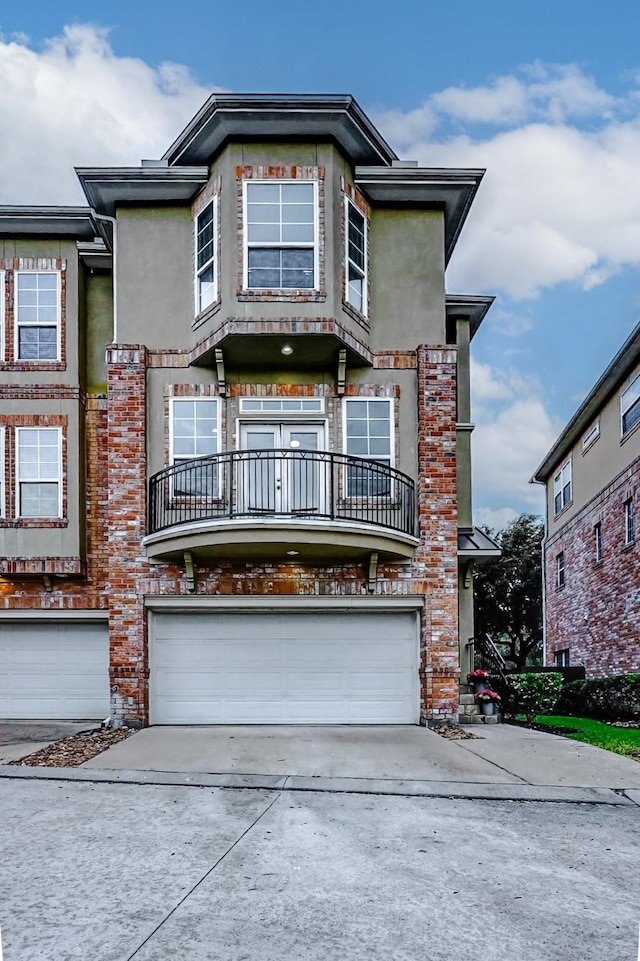 townhome / multi-family property with brick siding, a balcony, driveway, and an attached garage