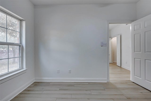 spare room with baseboards and light wood-type flooring