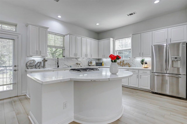 kitchen featuring visible vents, stainless steel appliances, white cabinets, and backsplash