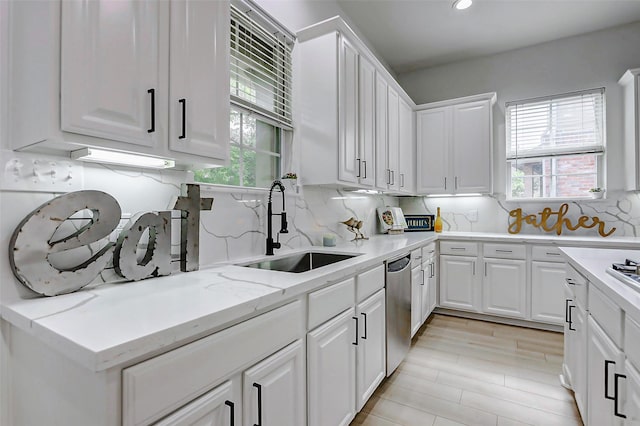 kitchen featuring light stone countertops, a sink, decorative backsplash, white cabinetry, and dishwasher