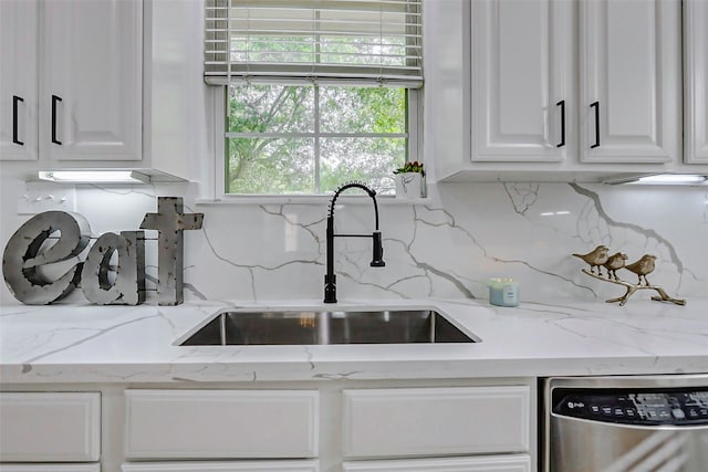 kitchen with a sink, decorative backsplash, light stone counters, stainless steel dishwasher, and white cabinets