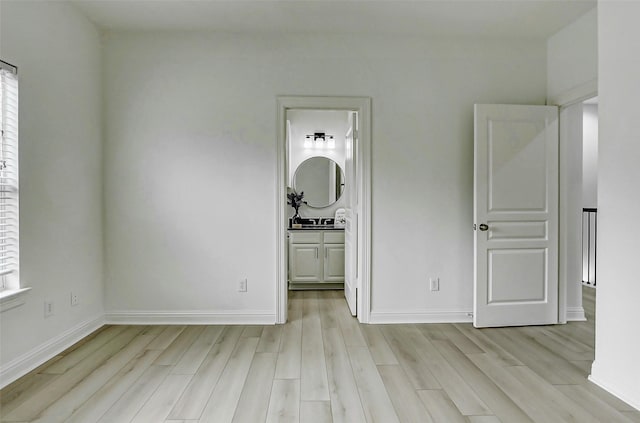unfurnished bedroom with multiple windows, light wood-style flooring, and baseboards