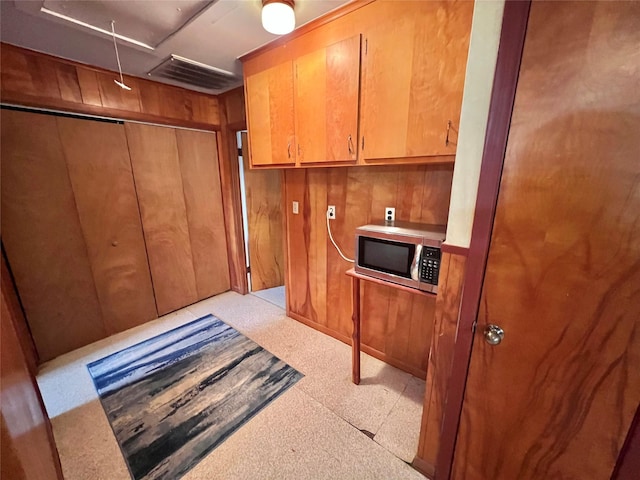 interior space with wooden walls, attic access, visible vents, and cabinet space