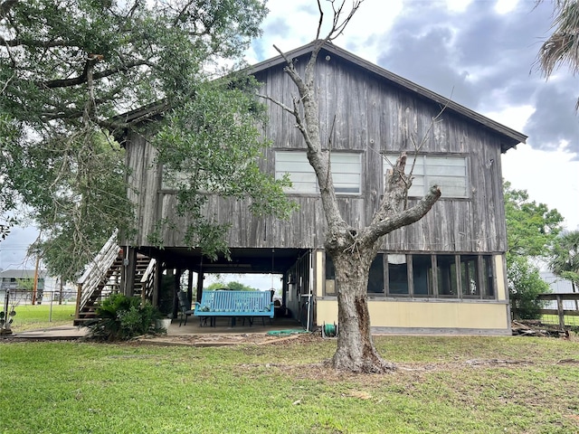 back of property featuring stairway and a lawn