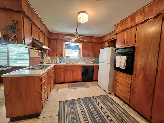 kitchen with a sink, brown cabinets, under cabinet range hood, black appliances, and a ceiling fan
