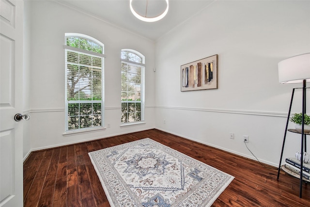 interior space with baseboards, ornamental molding, and wood finished floors