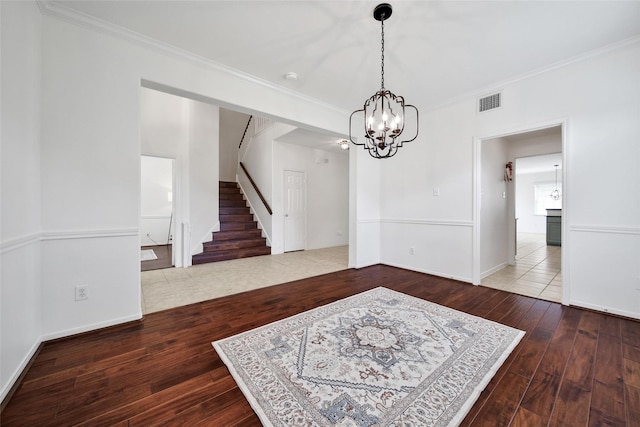 unfurnished dining area featuring a notable chandelier, stairs, wood-type flooring, and crown molding