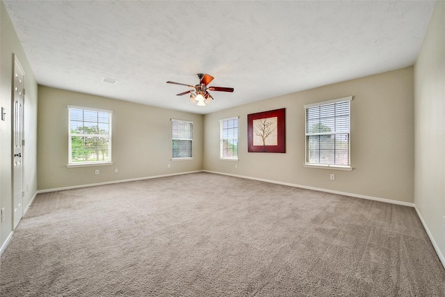 carpeted empty room featuring baseboards, visible vents, and a ceiling fan