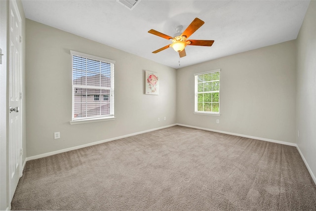 spare room with a ceiling fan, visible vents, carpet, and baseboards