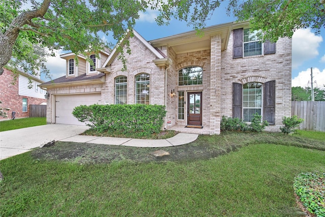 view of front of home with a front lawn, brick siding, concrete driveway, an attached garage, and fence