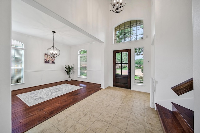 entrance foyer featuring an inviting chandelier, tile patterned floors, and plenty of natural light