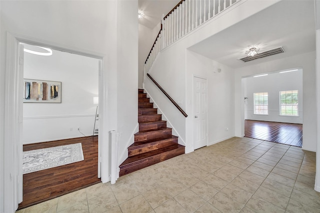 foyer entrance with stairway, baseboards, tile patterned flooring, and a high ceiling