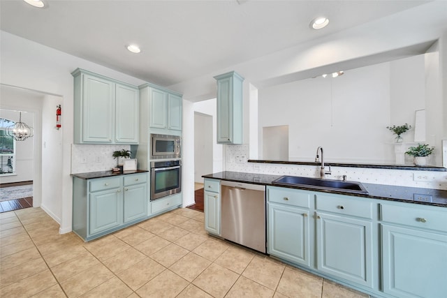 kitchen with light tile patterned floors, tasteful backsplash, a sink, appliances with stainless steel finishes, and a chandelier