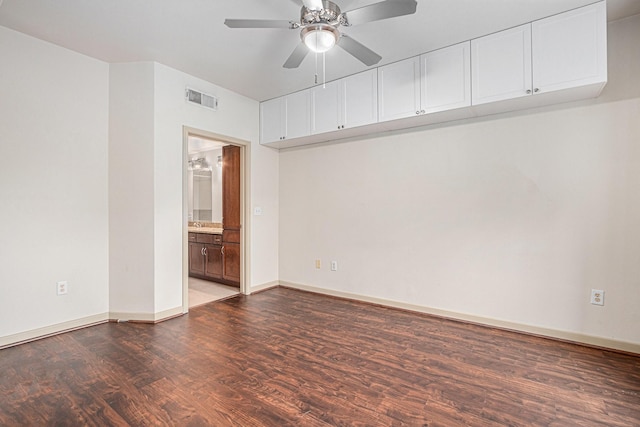 empty room with wood finished floors, ceiling fan, visible vents, and baseboards