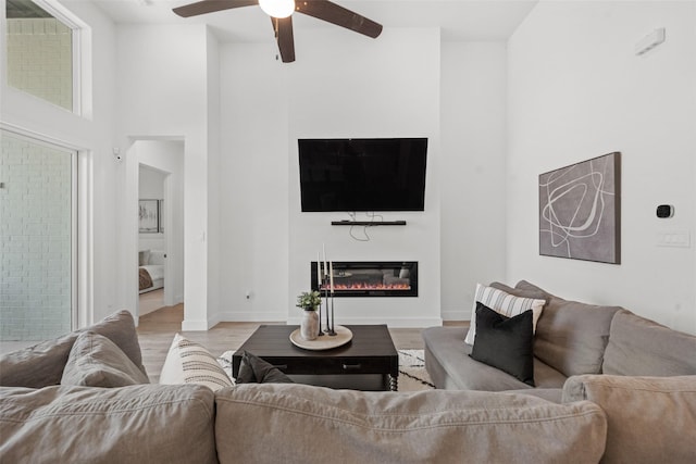 4623 Bridgewood Dr, Spring, TX 77386 - living area featuring wood finished floors, a glass covered fireplace, ceiling fan, baseboards, and a high ceiling